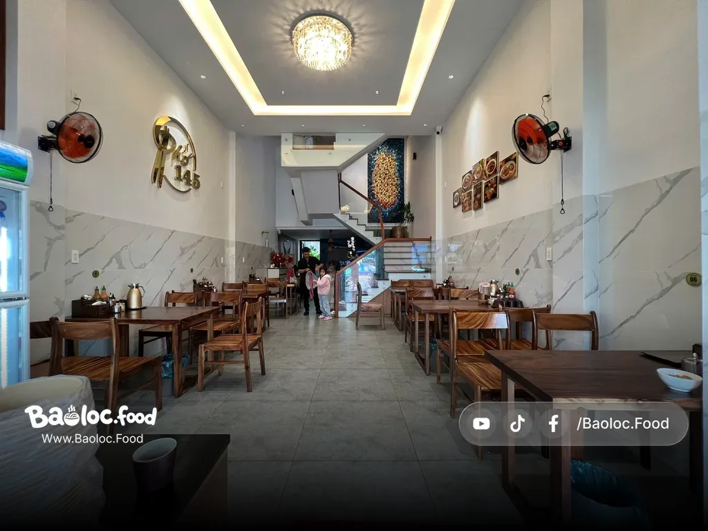 Khu vực bàn ghế gỗ trong Phở 145 Bảo Lộc, không gian sạch và thoáng